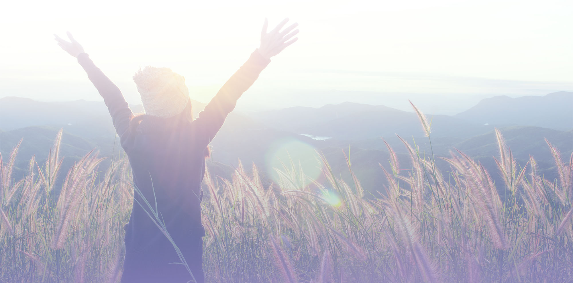 A previously depressed woman throwing her hands up in the air while hiking for mental health healing.